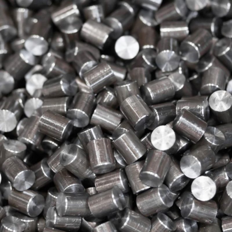 A pile of cylindrical metal rods, arranged closely together, with reflective tops and a uniform size.