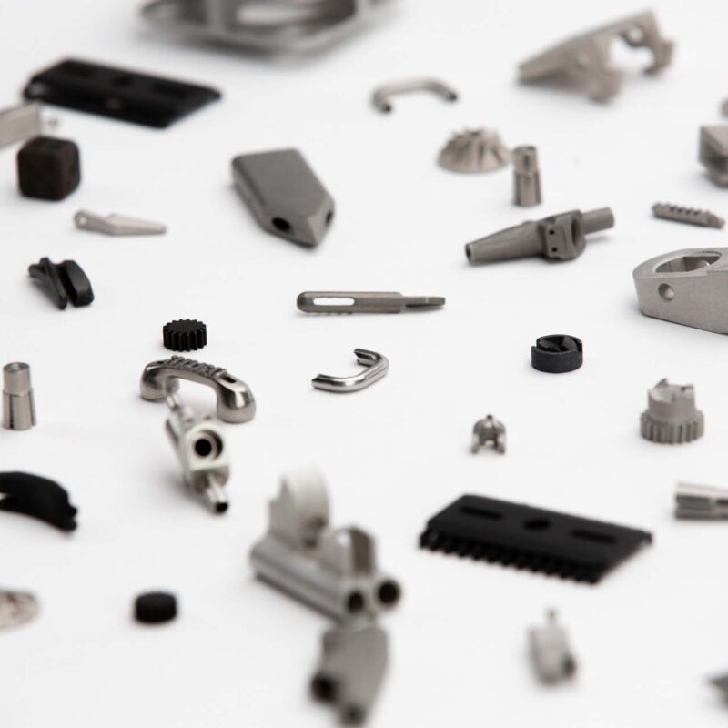 A collection of various small metallic machine parts and tools scattered on a white surface.