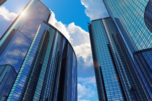 Modern skyscrapers with reflective glass facades crafted using metal 3D printing under a clear blue sky.