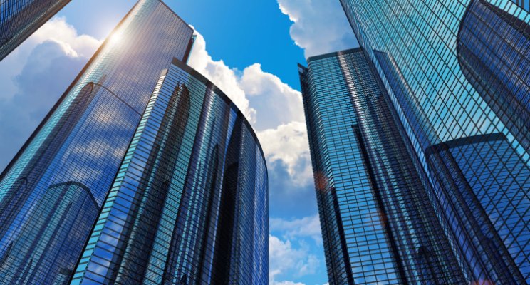 Modern skyscrapers with reflective glass facades crafted using metal 3D printing under a clear blue sky.