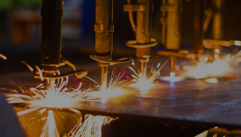 Automated welding machines operating on a 3D metal printing assembly line, emitting sparks during the manufacturing process.