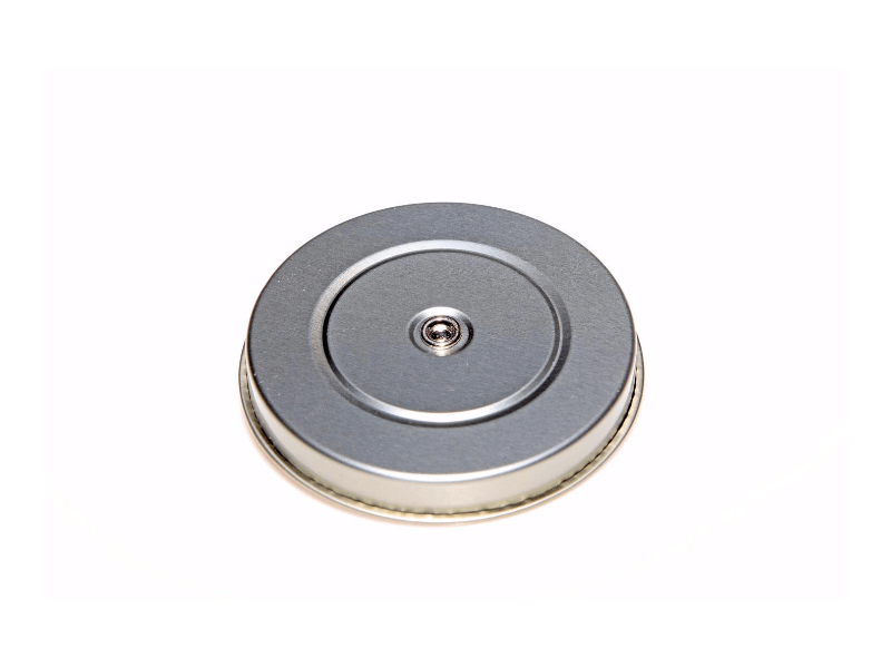 A round, metal object with a central protrusion on a white background.