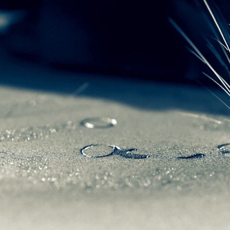 Close-up image of a metal surface with sparks flying from a point of contact where a laser cuts or engraves, highlighted by dramatic lighting.