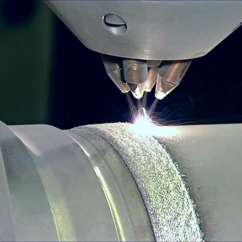 Close-up of a laser cutting machine precisely engraving a pattern on a cylindrical metal object, showcasing the integration of DED additive manufacturing for enhanced precision.