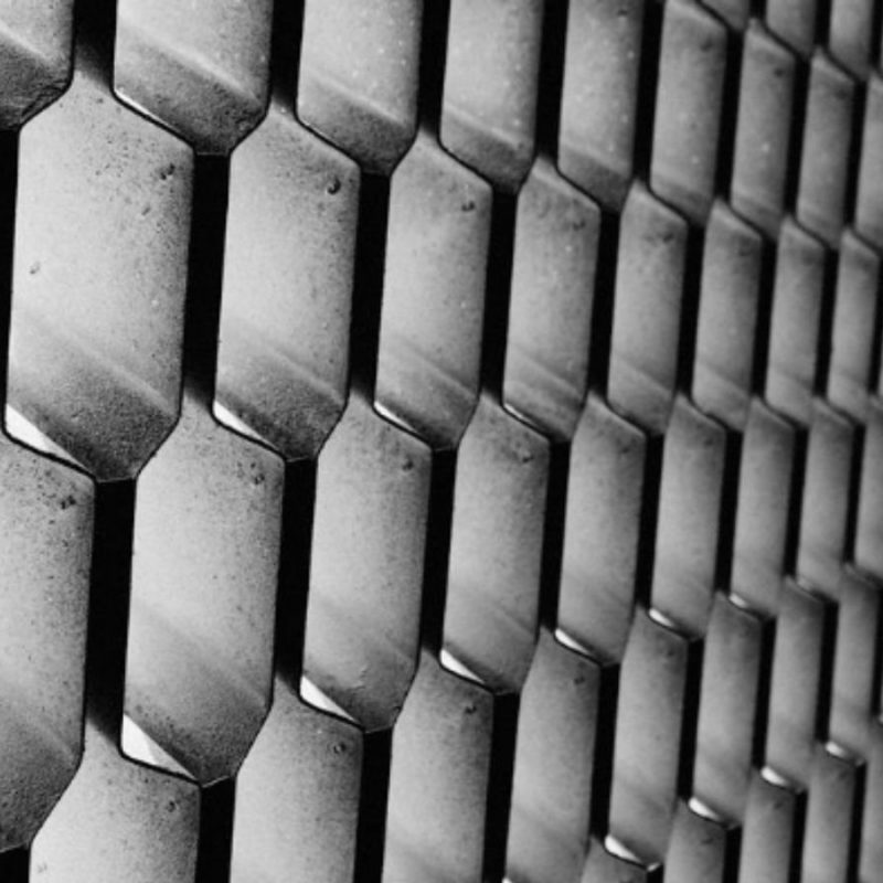 Black and white close-up of a textured wall featuring a repeating pattern of hexagonal shapes.