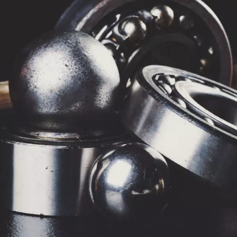 Close-up shot of assorted metal bearings and balls on a dark surface.