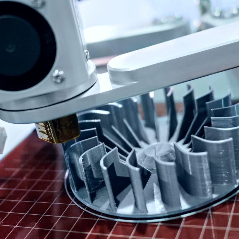 3d printer creating a detailed plastic turbine component, with the print head in focus and the object in partial view.