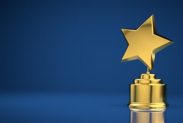 Gold star trophy on a pedestal against a blue background with a reflective surface.