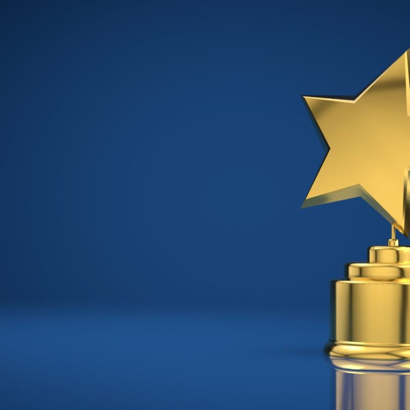 Gold star trophy on a pedestal against a blue background with a reflective surface.