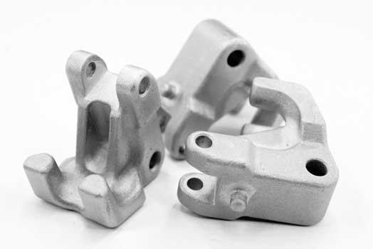 Three metal mechanical parts produced by 3D printing, with complex shapes on a white background.