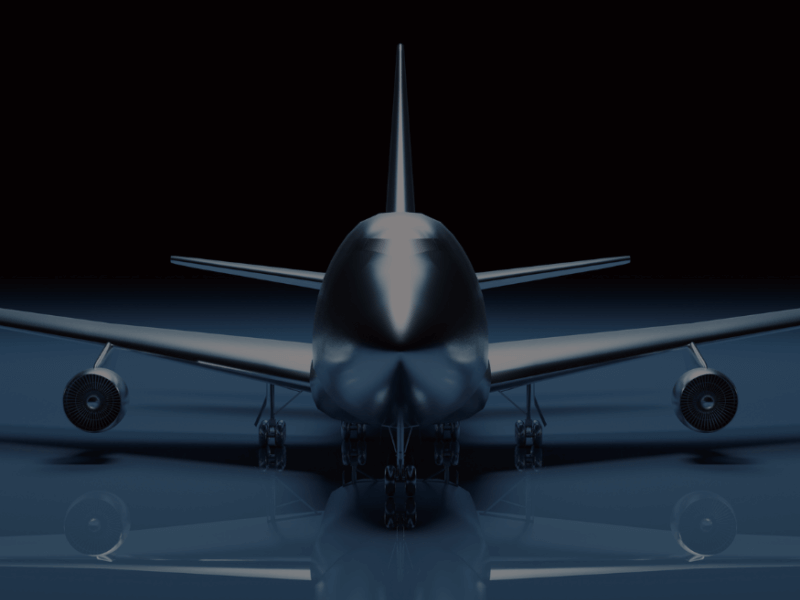 Front view of a large airplane with its landing gear down, set against a dark background with a slight reflection on the ground.