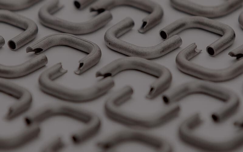 Close-up image of multiple U-shaped metal hooks arranged in neat rows on a gray surface.