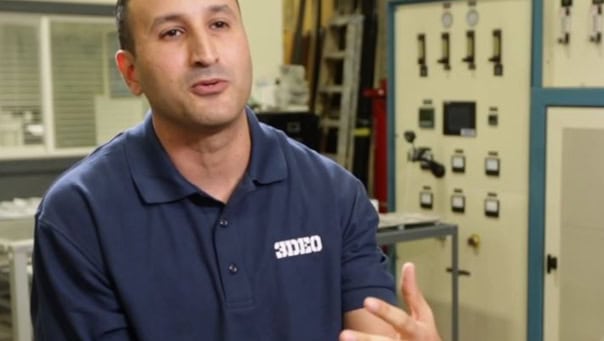 A man in a blue polo shirt with "3DEO" on it is speaking. He is in a room with industrial equipment and control panels in the background.
